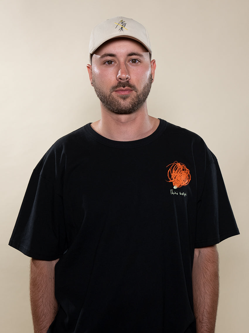 Founder Davis Rendle wearing the This is Burnt Tee and Do Not Pick Them recycled dad hat both created by maker Brent Lamb. The hat is made of recycled polyester and the tee is made of organic cotton to give a comfortable and soft feel