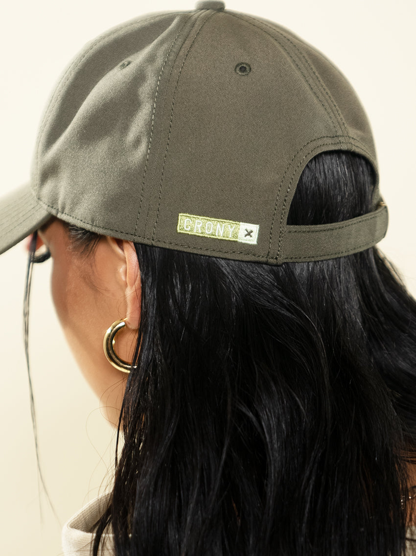 Female model wearing Peace in Death recycled dad hat. This shows a side back view with a close up of the CRONY X logo