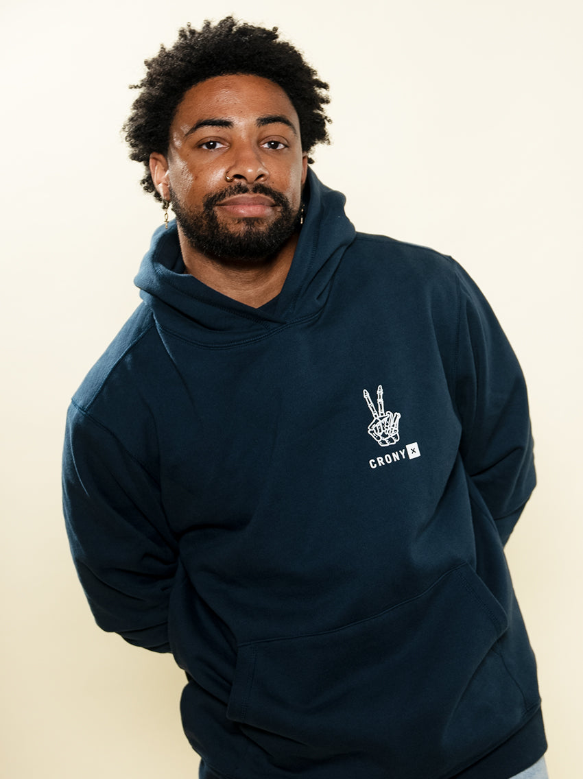Male model wearing navy Peace In Death hoodie. Designed by Founder Davis Rendle, this hoodie is made of premium, organic cotton giving it a soft and comfortable feel.