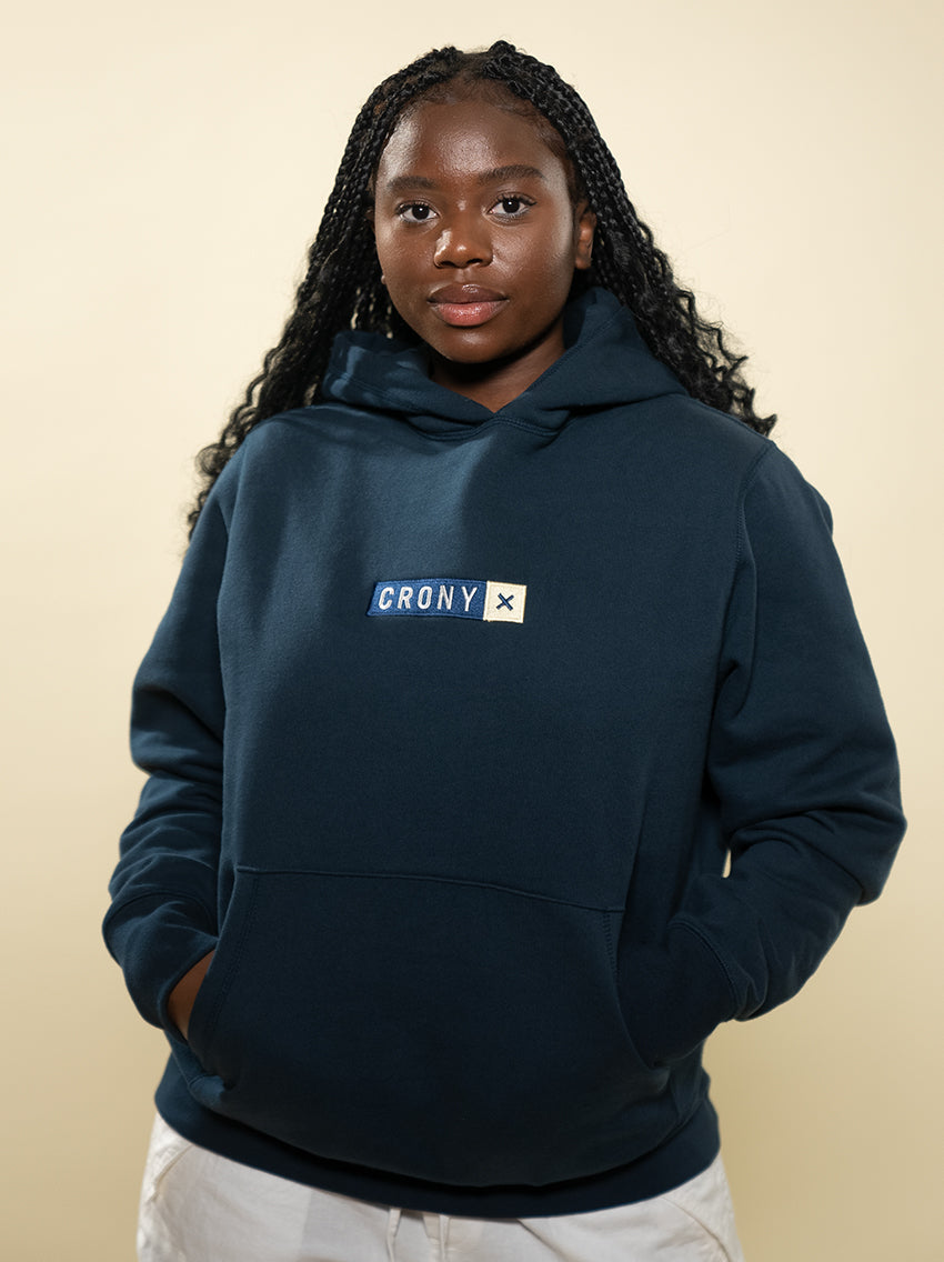 Female model wearing navy CRONY X branded hoodie. These are made of premium, organic cotton giving it a soft, comfortable feel