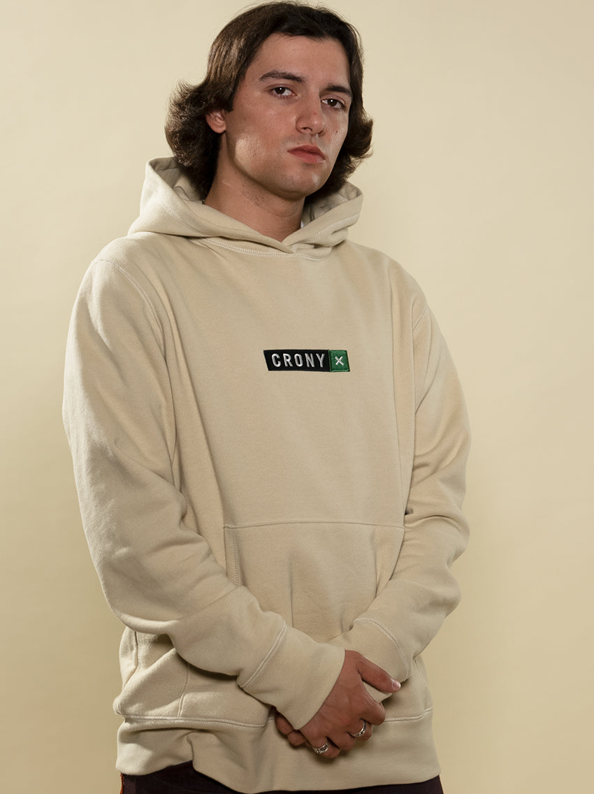 Male model wearing tan CRONY X branded hoodie. These are made of premium, organic cotton giving it a soft, comfortable feel